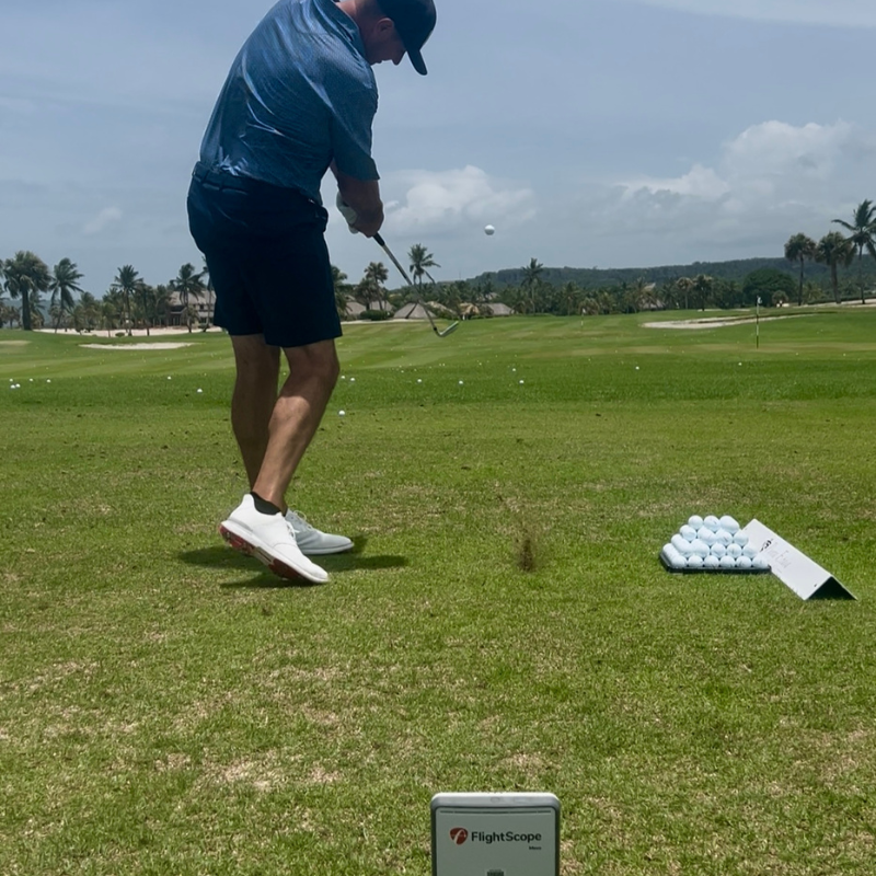 Flightscope Mevo Gen 2 launch monitor gebruik op de driving range door persoon die golfbal slaat waar de gegevens worden gemeten door de golf monitor