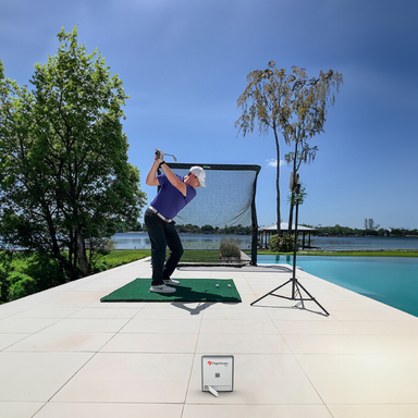 Mevo Gen 2 in gebruik met de net return golfnet in de tuin aan het water waarin een golfer de bal slaat