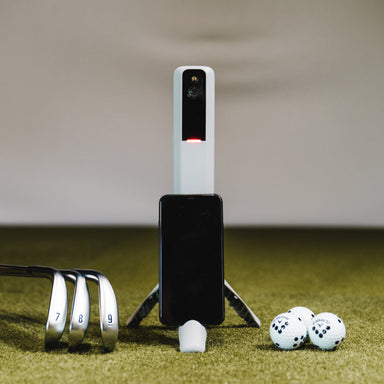 Rapsodo MLM2Pro launchmonitor achtergrond op gras met golfballen, golfclubs en telefoon